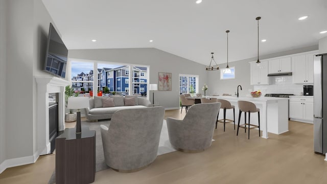 living room featuring light hardwood / wood-style floors, lofted ceiling, and sink