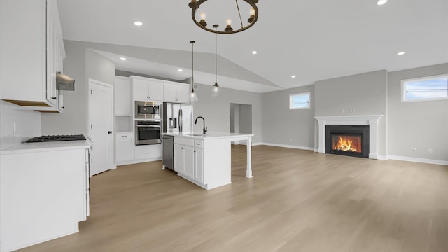 kitchen featuring an island with sink, a healthy amount of sunlight, white cabinets, and lofted ceiling