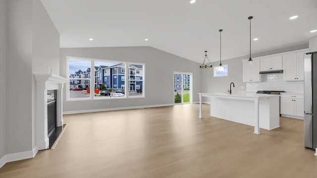 kitchen featuring light wood-type flooring, pendant lighting, an island with sink, and white cabinets