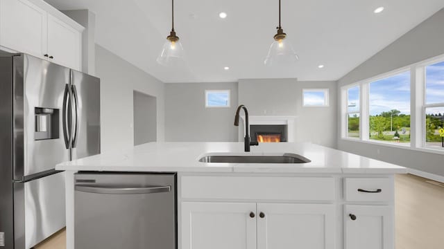 kitchen with stainless steel appliances, white cabinetry, pendant lighting, sink, and vaulted ceiling