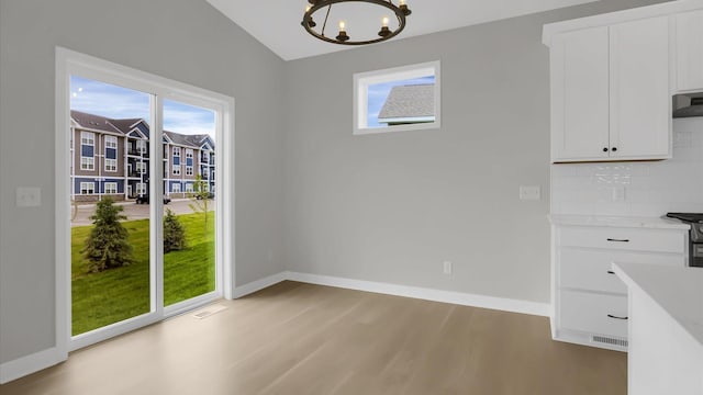 unfurnished dining area featuring a healthy amount of sunlight, light wood-type flooring, and lofted ceiling