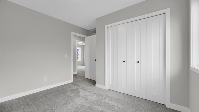 unfurnished bedroom featuring light carpet and a closet