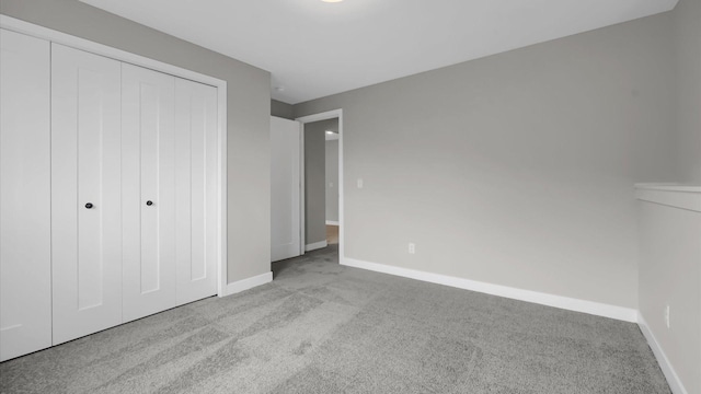 unfurnished bedroom with a closet and light colored carpet