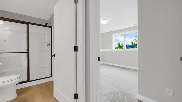 bathroom featuring toilet and a shower with door