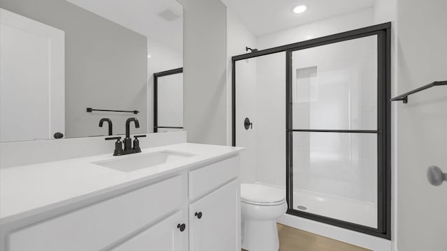 bathroom with toilet, vanity, wood-type flooring, and a shower with shower door