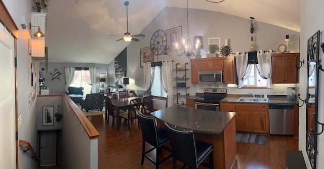 kitchen featuring sink, dark hardwood / wood-style flooring, a kitchen bar, ceiling fan with notable chandelier, and appliances with stainless steel finishes