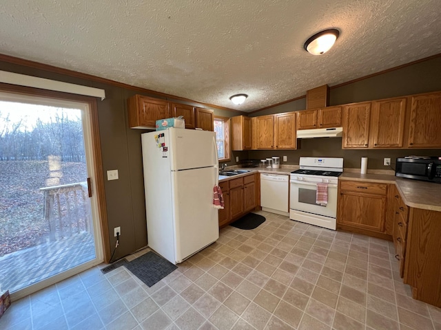 kitchen featuring sink, white appliances, a textured ceiling, and lofted ceiling