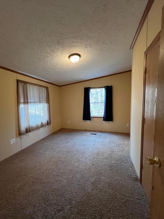 unfurnished room with light colored carpet, a textured ceiling, and ornamental molding