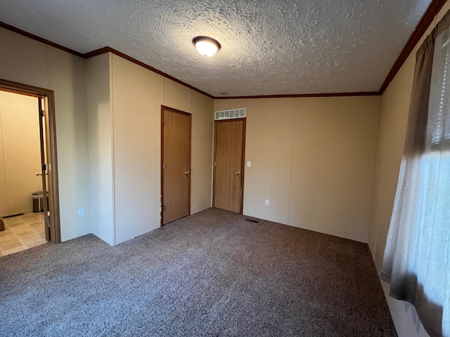 unfurnished bedroom featuring ensuite bath, a textured ceiling, and light carpet