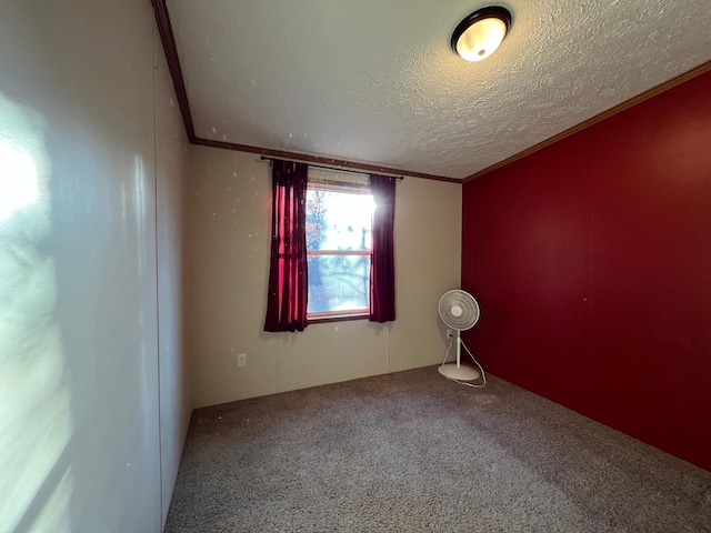 spare room featuring lofted ceiling, a textured ceiling, carpet floors, and crown molding