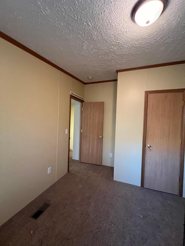 empty room featuring a textured ceiling, carpet flooring, and crown molding