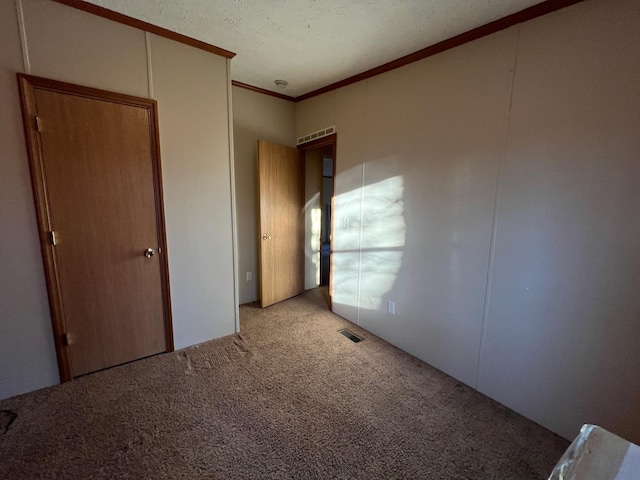 unfurnished bedroom with ornamental molding, a textured ceiling, and light carpet