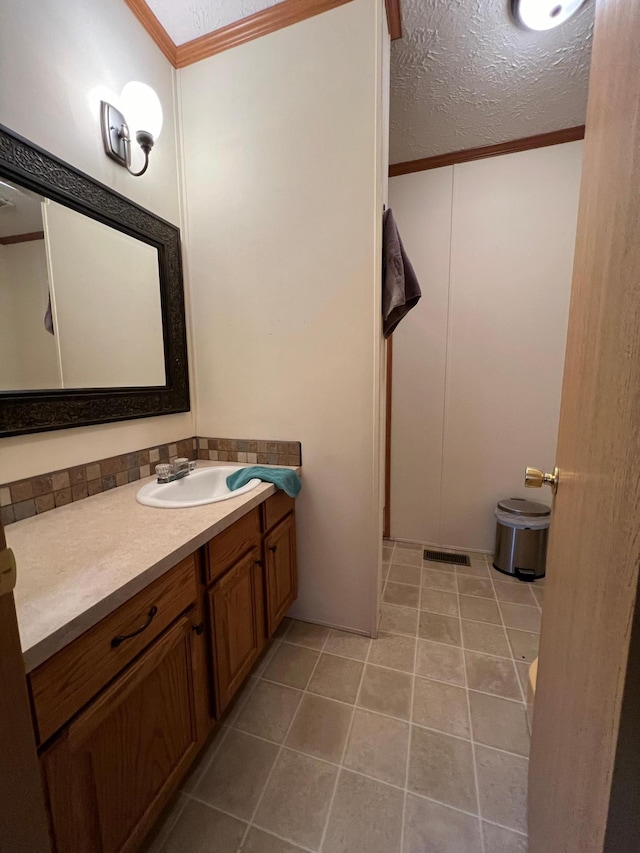 bathroom with vanity, a textured ceiling, tile patterned floors, and crown molding