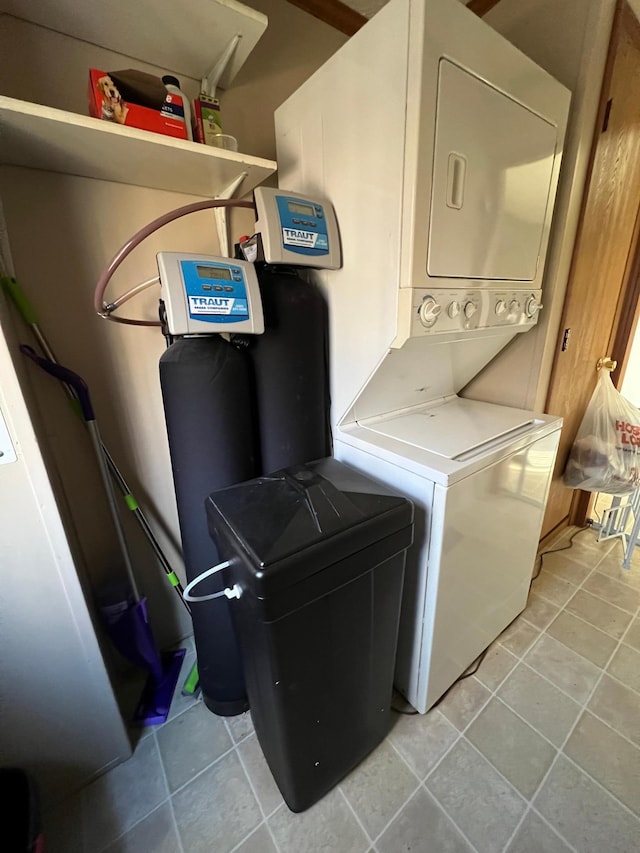 washroom with stacked washer and dryer and light tile patterned floors