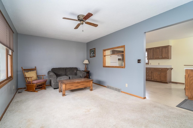 living area with ceiling fan and light colored carpet