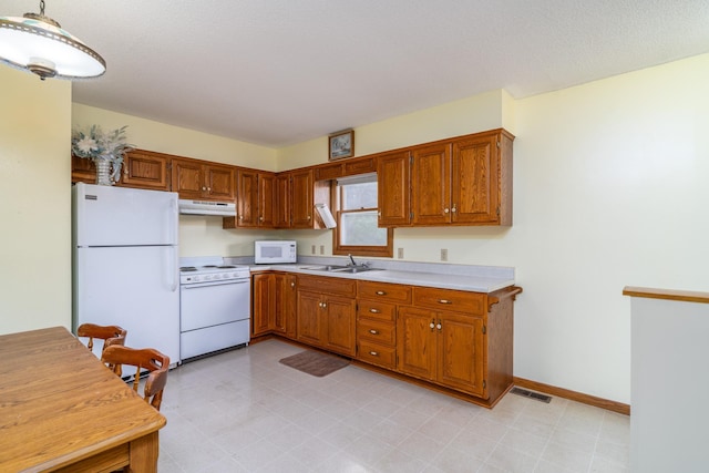 kitchen with hanging light fixtures, sink, and white appliances