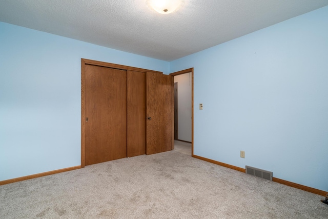 unfurnished bedroom with light carpet, a closet, and a textured ceiling