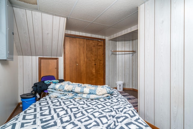 bedroom with a closet and wooden walls