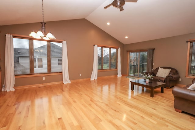 living room featuring ceiling fan with notable chandelier, light hardwood / wood-style floors, and vaulted ceiling