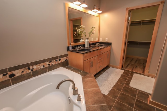 bathroom with a washtub, vanity, and tile patterned floors