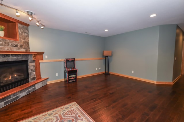 unfurnished living room featuring a fireplace, dark hardwood / wood-style flooring, and rail lighting