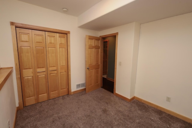 unfurnished bedroom with dark colored carpet and a closet