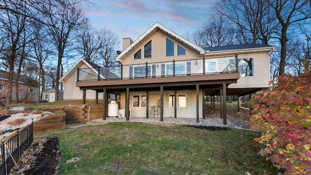 back house at dusk featuring a lawn and a deck