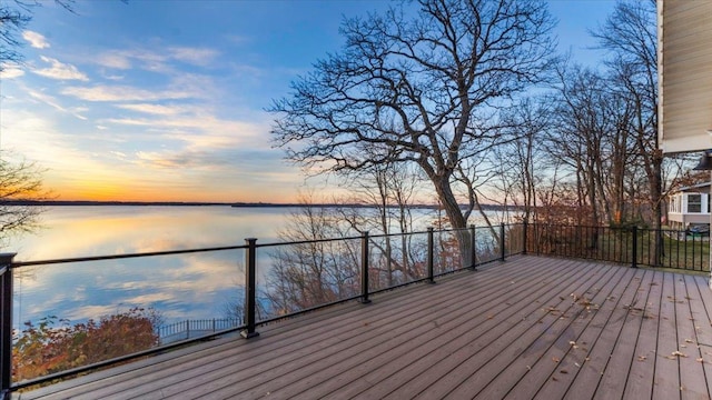 deck at dusk featuring a water view