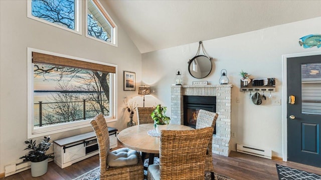 dining area with a fireplace, vaulted ceiling, plenty of natural light, and a baseboard heating unit