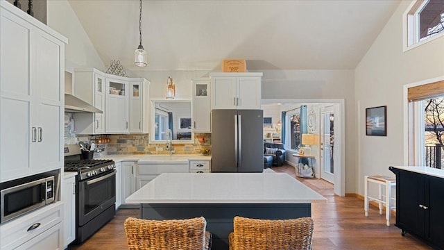 kitchen with backsplash, white cabinetry, a kitchen island, and stainless steel appliances