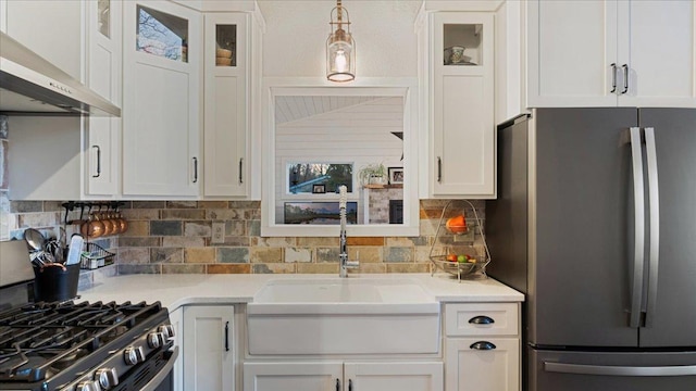 kitchen featuring appliances with stainless steel finishes, tasteful backsplash, wall chimney exhaust hood, sink, and white cabinets