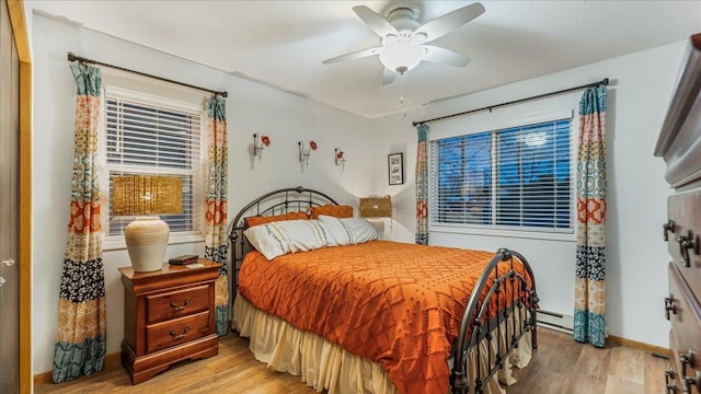 bedroom featuring light hardwood / wood-style floors, a baseboard radiator, and ceiling fan