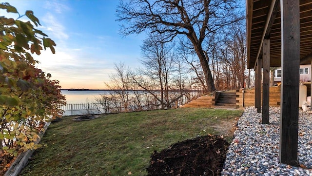 yard at dusk featuring a water view