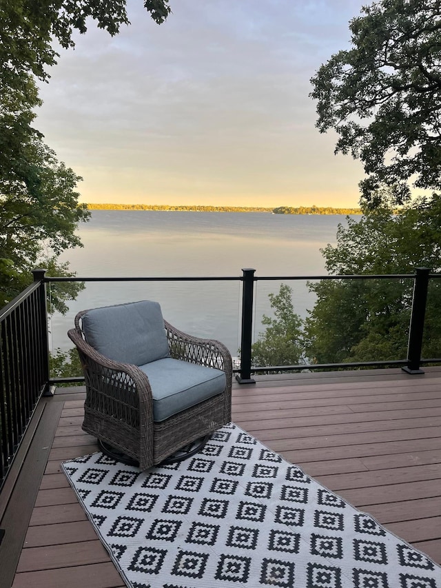 deck at dusk featuring a water view