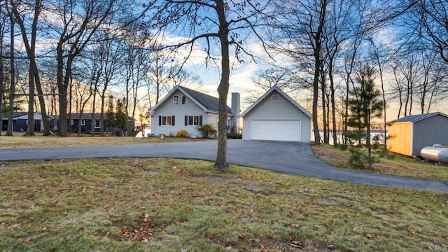 view of front of home featuring a garage, a storage shed, and a front yard