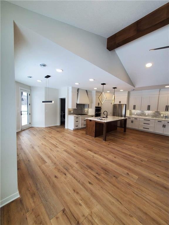 kitchen with white cabinets, decorative light fixtures, light hardwood / wood-style floors, and tasteful backsplash