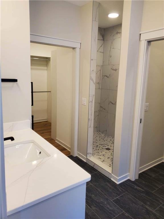 bathroom with vanity, a tile shower, and wood-type flooring