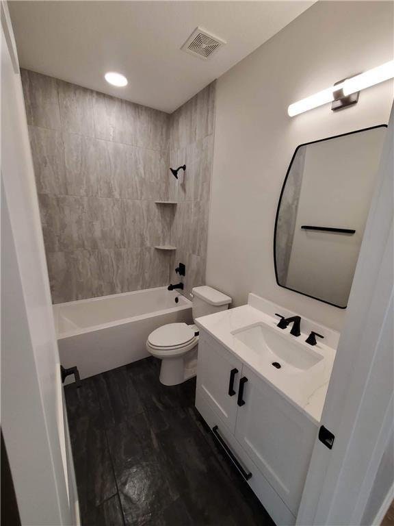 full bathroom with hardwood / wood-style floors, tiled shower / bath combo, toilet, and vanity