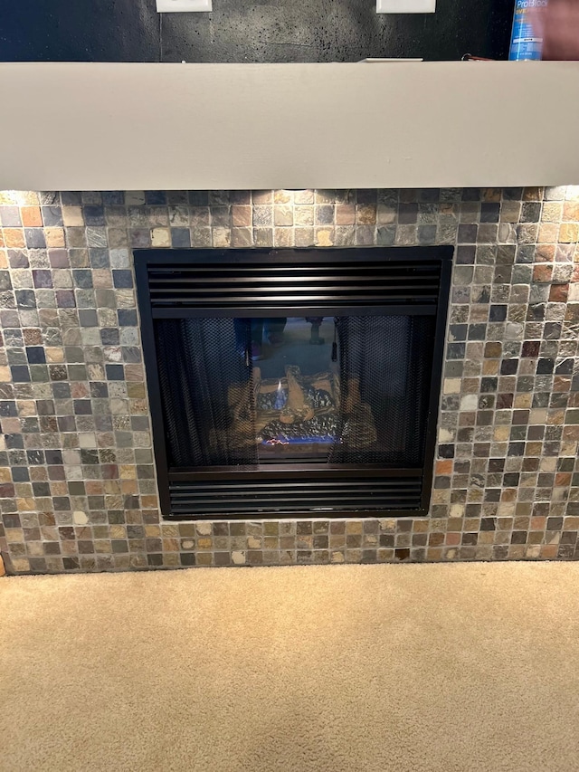 details featuring a tiled fireplace and carpet flooring