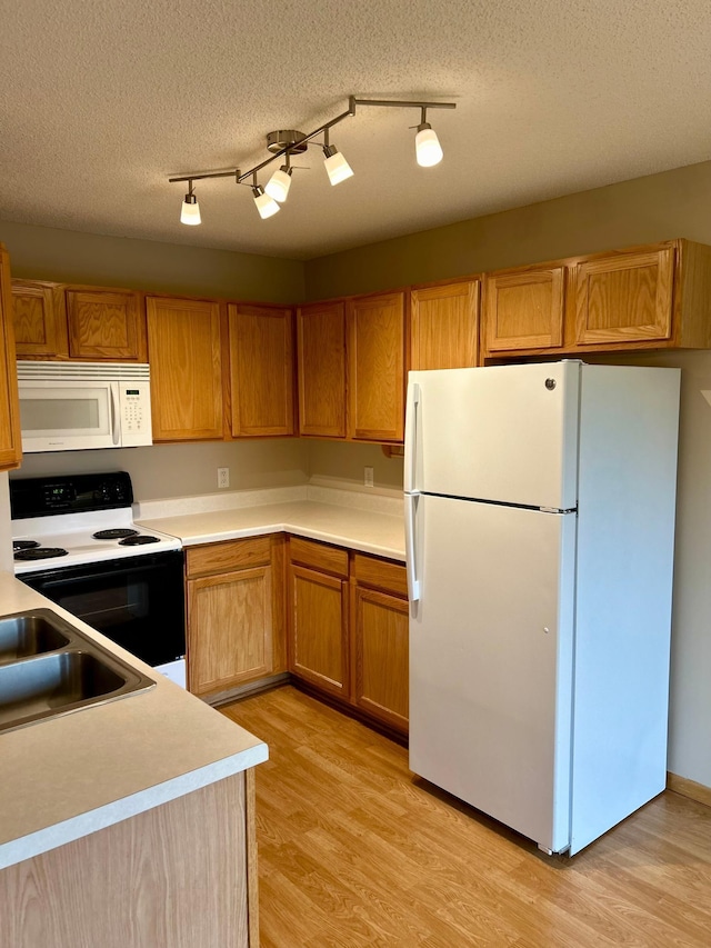 kitchen featuring white appliances, a textured ceiling, track lighting, and light hardwood / wood-style flooring