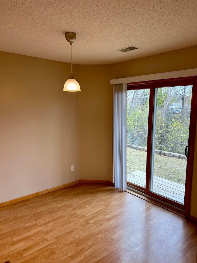 spare room with a textured ceiling and light hardwood / wood-style flooring