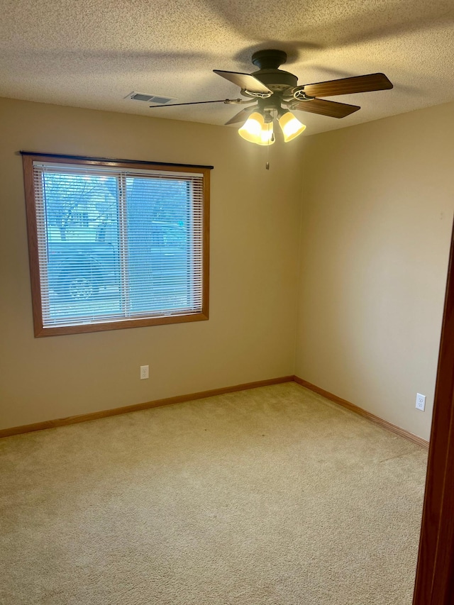 carpeted spare room featuring a textured ceiling and ceiling fan