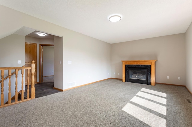 unfurnished living room with a premium fireplace and dark colored carpet