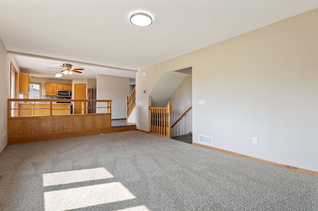 unfurnished living room with ceiling fan and carpet