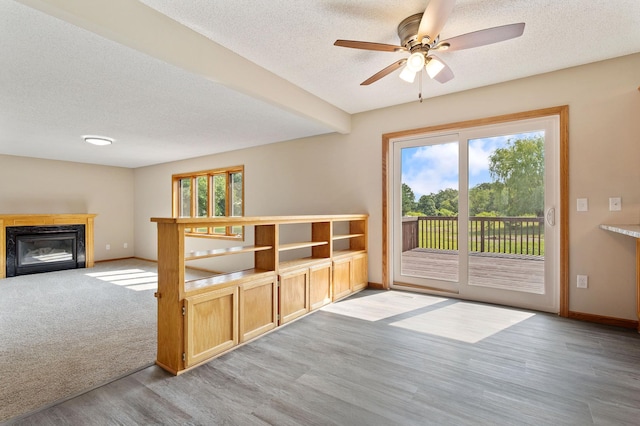 unfurnished living room featuring a textured ceiling, a healthy amount of sunlight, and light colored carpet