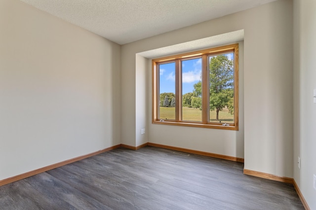 empty room featuring a textured ceiling and dark hardwood / wood-style floors