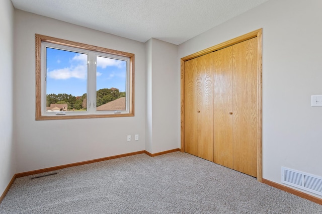 unfurnished bedroom featuring light colored carpet, a closet, and a textured ceiling