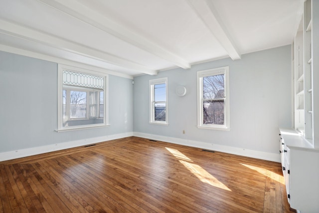 empty room with hardwood / wood-style floors and beamed ceiling