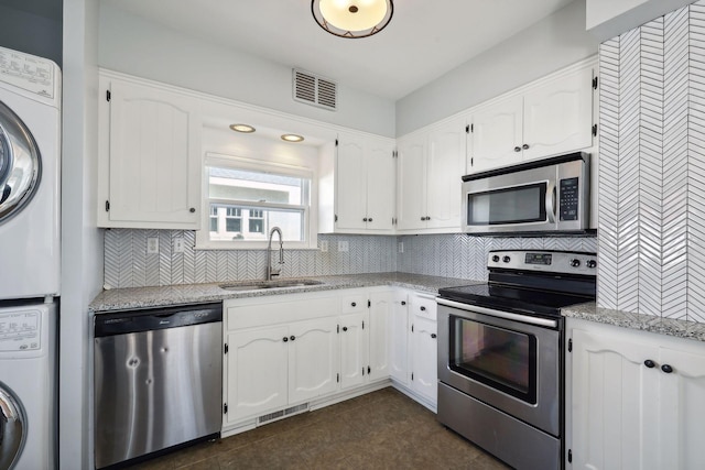 kitchen with white cabinetry, sink, stacked washer / dryer, and appliances with stainless steel finishes