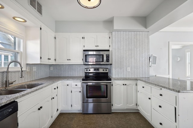 kitchen with white cabinetry, sink, light stone counters, and appliances with stainless steel finishes